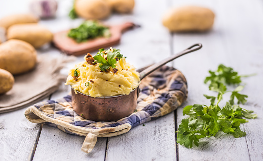 Mashed potatoes in old panl decorated parsley herbs and roasted bacon pieces.