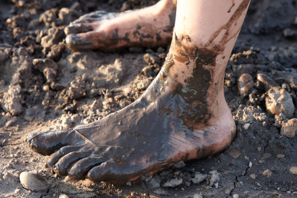 two children's feet walk barefoot in the mud
