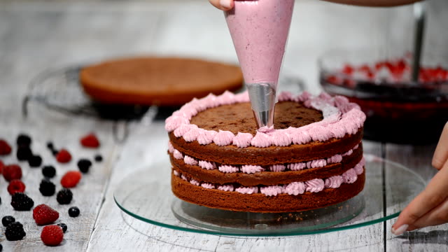 Confectioner is decorating chocolate cake.