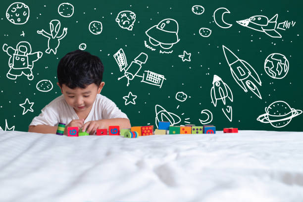 istock Asian kid learning by playing with his imagination about science and space adventure, hand drawn on the green chalkboard, education back to school and discovery concept. 1043532106
