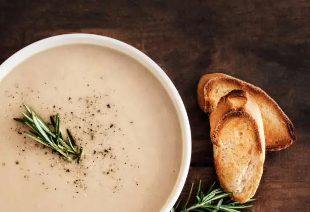 Homemade Mushroom cream soup with herbs and spices. Cream-soup on wooden table. Top view"n