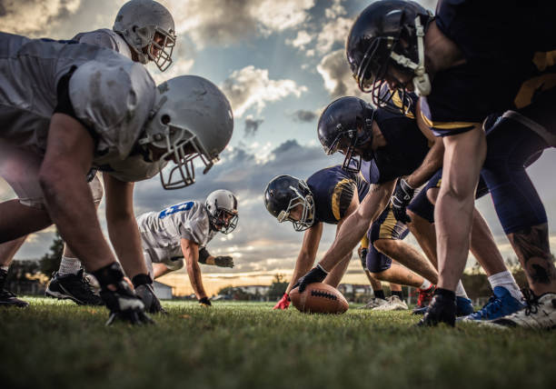 sotto la vista dei giocatori di football americano all'inizio della partita. - offensive line foto e immagini stock