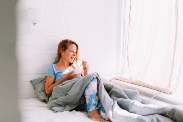 istock Young woman eating breakfast in bed 1043546156