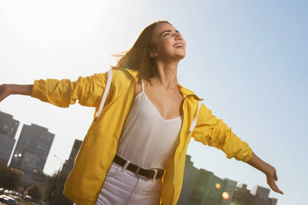 donna felice che gode della libertà all'aperto sullo sfondo del cielo con le mani alzate - giacca a vento foto e immagini stock