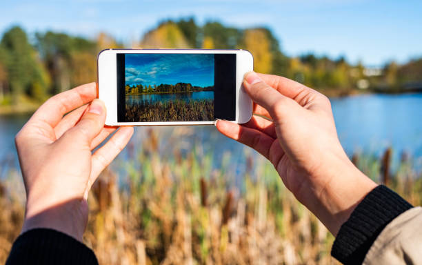 Close up of woman taking picture of lake.