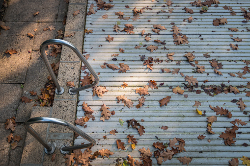 Closes swimming pool with coloful leaves on the cover in autumn symbolizing summer season is over