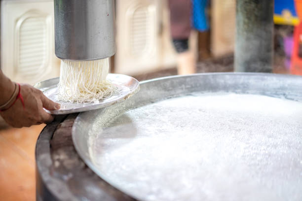 Thai chef making fresh noodles in a restaurant.