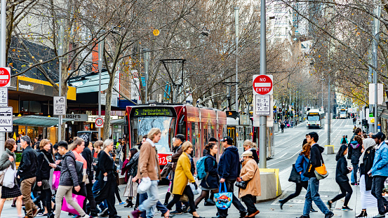 Melbourne, Victoria, Australia, July 14 2018: Five Public Transport Victoria trams are on Swanston Street while pedestrians cross the road at the intersection of Bourke Street.