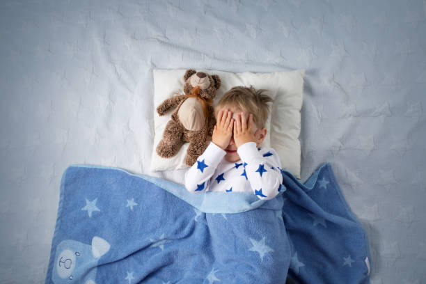 niño de tres años de edad llorando en la cama - bedroom blue bed domestic room fotografías e imágenes de stock