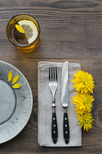 istock Rustic table setting with linen napkin, cutlery, ceramic plates, yellow glasses and yellow flowers 1043565088