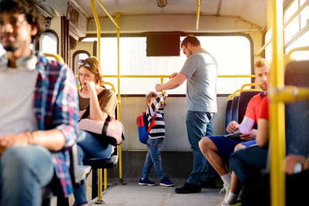 Picture of father and son standing at the end of the bus and holding for a bar. Picture of father and son standing at the end of the bus and holding for a bar. urgency mother working father stock pictures, royalty-free photos & images