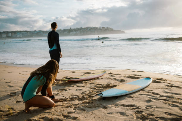 istock Two young women putting on wet suits for surfing 1043566070