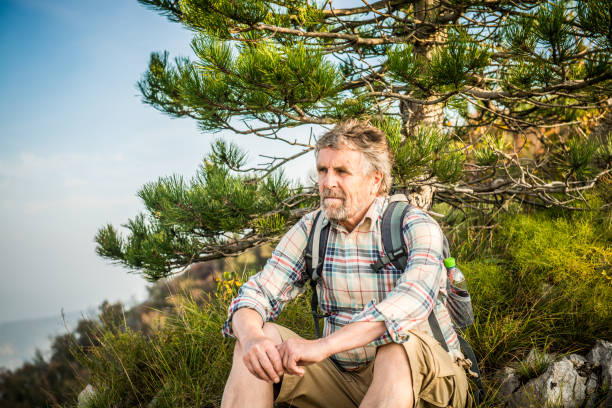 istock Senior Man sitting on top of a Mountain 1043573952