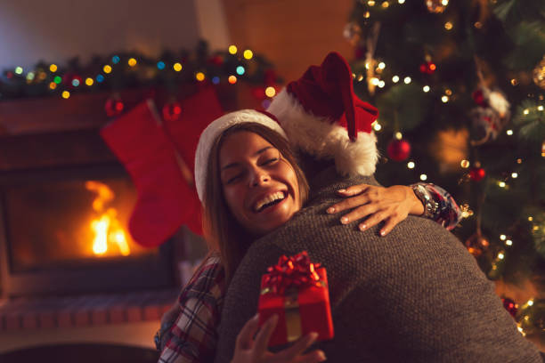 Couple exchanging Christmas presents Young couple in love sitting by the fireplace and nicely decorated Christmas tree, exchanging Christmas presents gift for girlfriend stock pictures, royalty-free photos & images