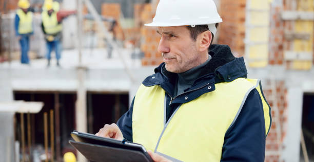 istock Male architect standing at construction site and checking plans on digital tablet 1043577240