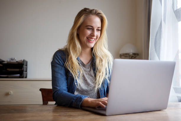 istock happy young blond woman using laptop at home 1043584470