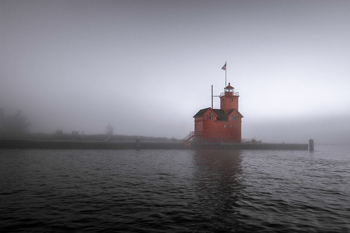 The Holland Michigan lighthouse known as Big Red encased in fog on the shores of Lake Michigan.