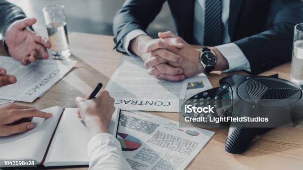 Cropped Shot Of Business People Having Conversation With Documents And Speakerphone On Table At Modern Office Stock Photo - Download Image Now