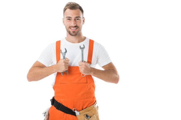 istock smiling handsome auto mechanic in orange uniform showing wrenches isolated on white 1043601278
