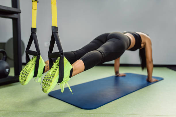 Workount at the gym. Fit girl doing plank exercise on trx for back spine and posture suspension training stock pictures, royalty-free photos & images