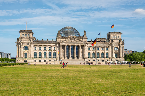 Berlin, Germany - May 28, 2017: Reichstag building, German Parliament (Deutscher Bundestag), people enjoying a spring day. The dedication Dem deutschen Volke, meaning To the German people, can be seen on the frieze.