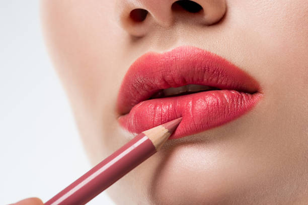 vista recortada de mujer aplicar lápiz de labios, aislado en blanco - lip liner fotografías e imágenes de stock
