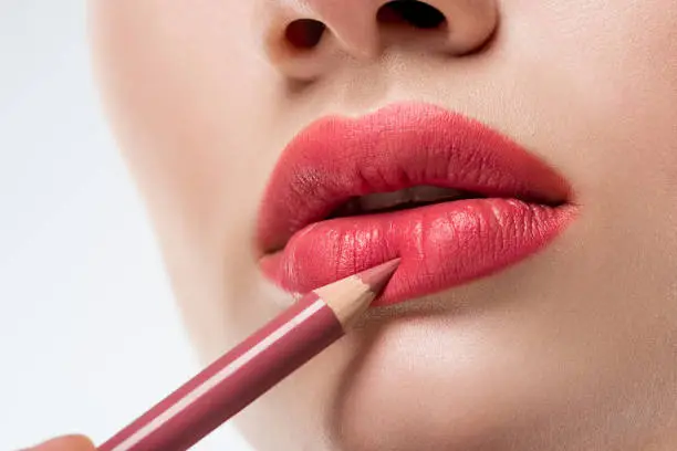 cropped view of woman applying lip pencil,  isolated on white