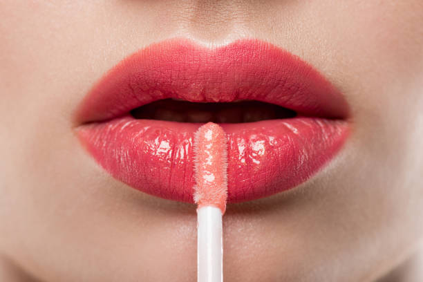 primer plano de mujer joven aplicar brillo de labios - gloss de labios fotografías e imágenes de stock