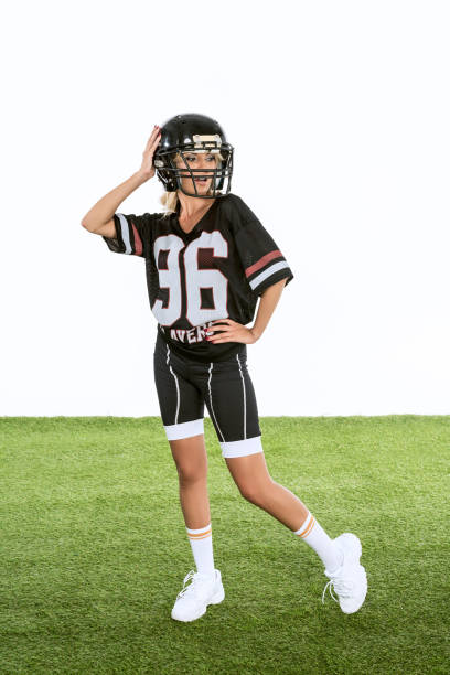 立っているアメリカン フットボール制服白で隔離緑の草の上に魅力的な若い女性 - football helmet american football green american football uniform ストックフォトと画像
