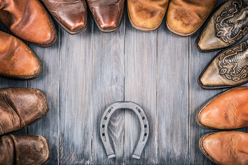 Concepto de fondo madera salvaje oeste con botas vaqueras de cuero retro y la herradura. Foto filtrada de estilo vintage photo