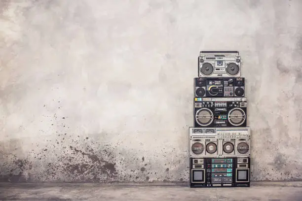 Photo of Retro old school design ghetto blaster boombox stereo radio cassette tape recorders tower from circa 1980s front concrete wall background. Vintage style filtered photo