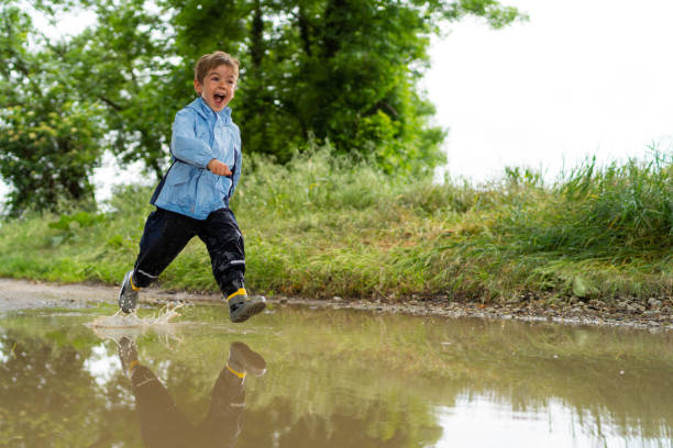 istock overjoyed little boy running through rain puddle 1043633814