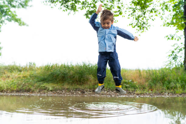 istock little boy jumping in rain puddle 1043633820
