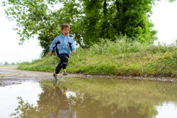 istock very happy little boy running through rain puddle 1043633830