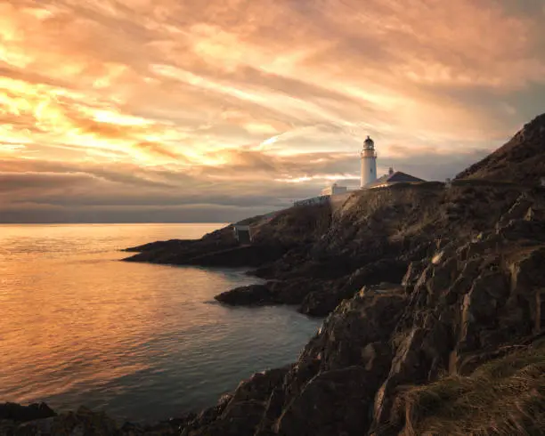 Beautiful dramatic skies at sunrise over Douglas Lighthouse, Isle of Man, with high interesting cloud formation.