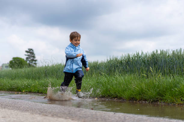 istock one little boy running through rain puddle 1043633876