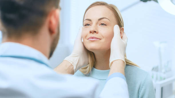 plástico / rostro de la mujer hermoso examina cirujano cosméticos, lo toca con las manos enguantadas, inspección de cara curado después de cirugía con resultados espectaculares. - spa treatment fotografías e imágenes de stock