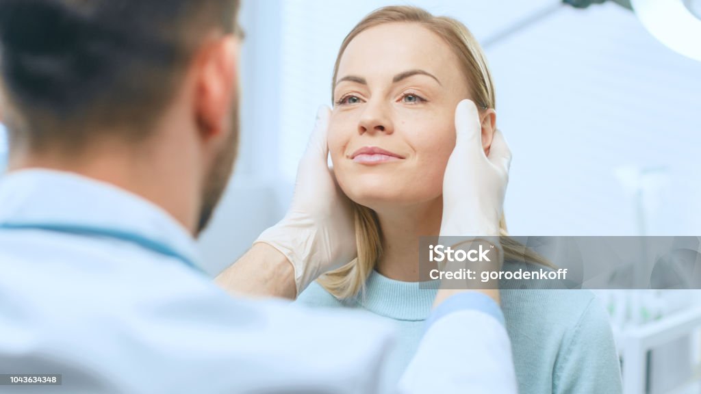 Plastic / Cosmetic Surgeon Examines Beautiful Woman's Face, Touches it with Gloved Hands, Inspecting Healed Face after Plastic Surgery with Amazing Results. Plastic Surgery Stock Photo