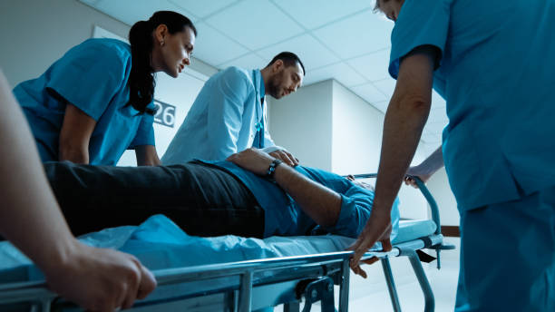 emergency department: doctors, nurses and paramedics run and push gurney / stretcher with seriously injured patient towards the operating room. bright modern hospital with professional staff. - stretcher imagens e fotografias de stock