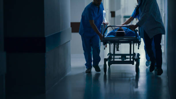 pronto soccorso: medici, infermieri e paramedici spingono gurney / barella con paziente gravemente ferito verso la sala operatoria. - gruppo medio di persone foto e immagini stock