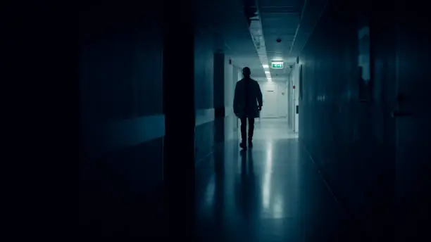Photo of Medical Doctor Silhouette Walks in Dark Part of the Hospital Corridor.