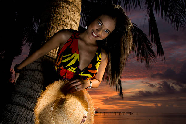 Straw hat resting among the green fronds and red fruit of a palm tree