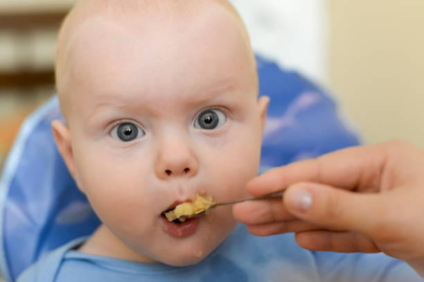 istock Mom feeds her son from a spoon with applesauce 1043640620