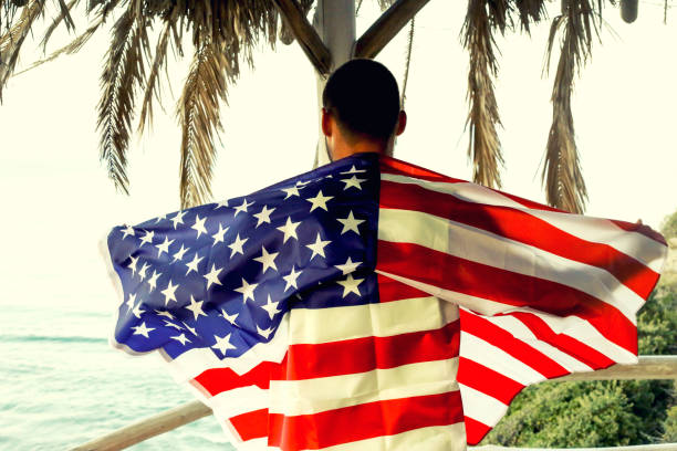 istock Young man holding the American flag on the beach 1043647970