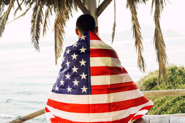 istock Young man holding the American flag on the beach 1043648618