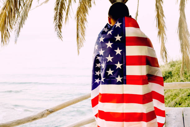 istock Young man holding the American flag on the beach 1043648958