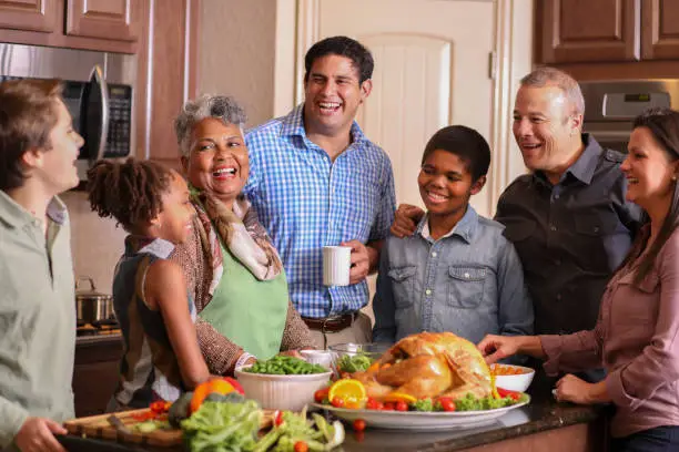 Photo of Diverse family in home kitchen cooking Thanksgiving dinner.