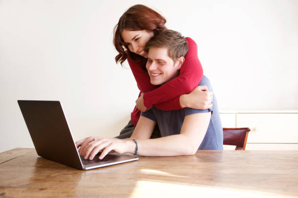 happy boyfriend and girlfriend using laptop computer at home