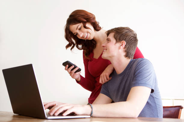 happy boyfriend and girlfriend using laptop computer and mobile phone