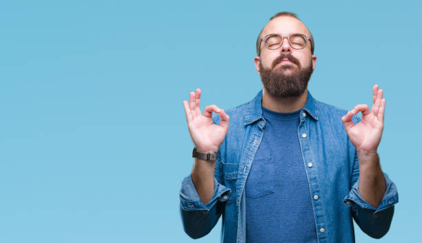 usa gafas de hombre de joven inconformista caucásico sobre fondo aislado relajación y sonreír con los ojos cerrados haciendo gesto de meditación con los dedos. concepto de yoga. - gente tranquila fotografías e imágenes de stock